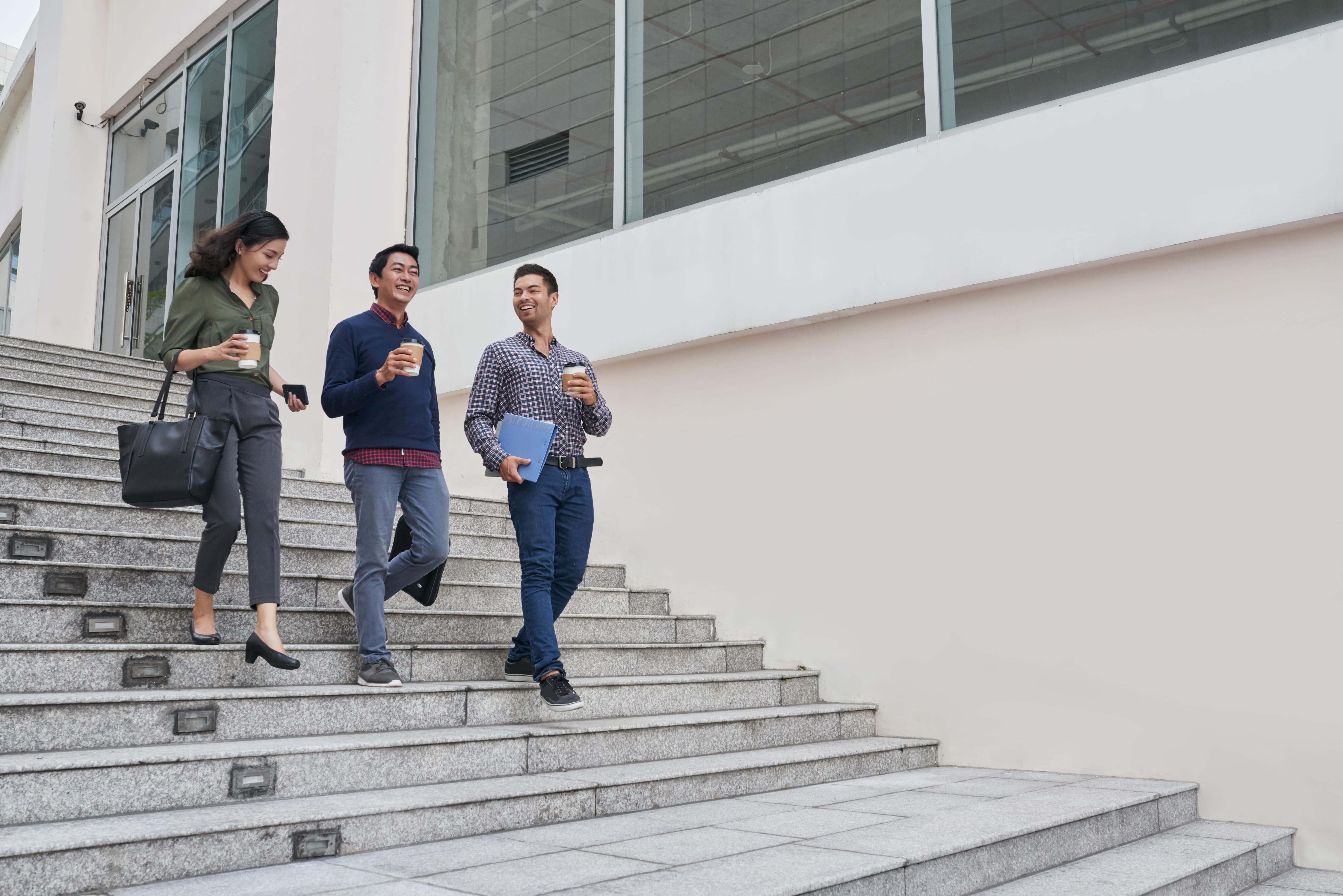 Campus universitario con estudiantes caminando y usando dispositivos móviles